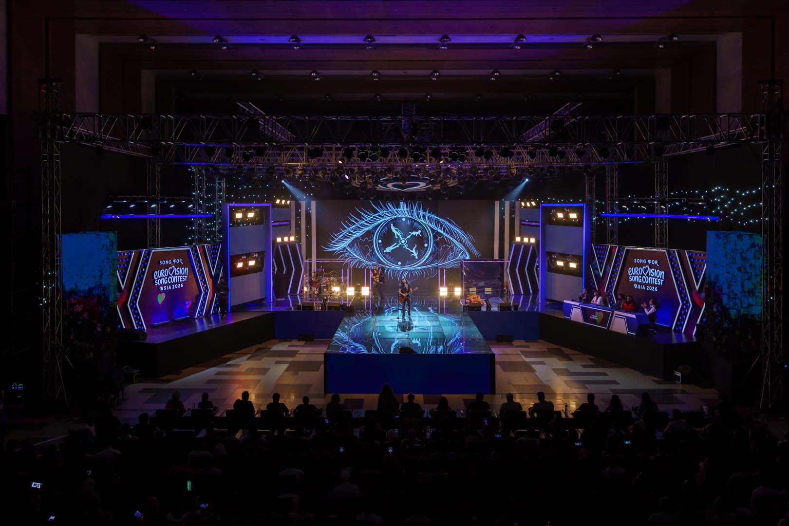 Large blue eye graphic on the LED wall with a performer below